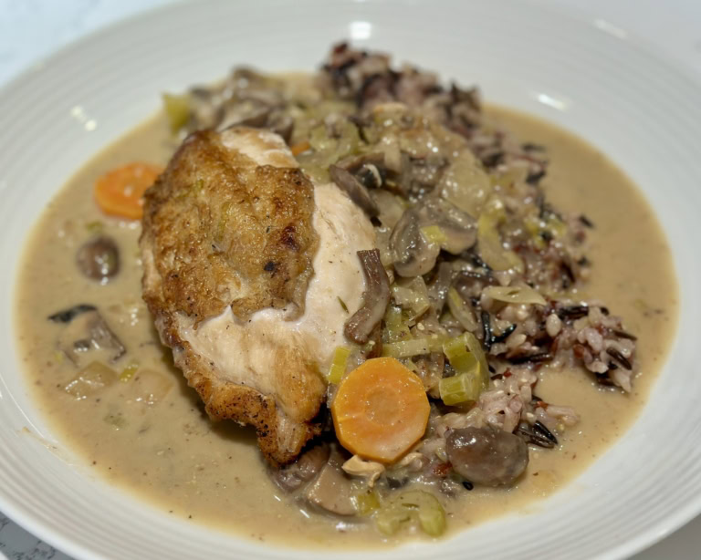 Golden-brown chicken with creamy, vegetable-infused sauce over flavorful rice.