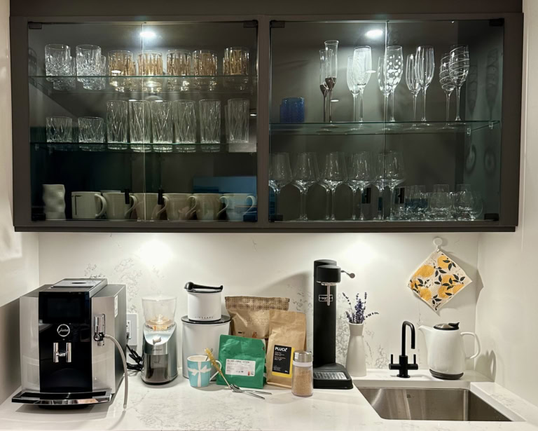 Modern kitchen corner with espresso machine, glassware, and coffee products.