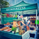 A vibrant farm market stall featuring fresh greens, baked goods, and homemade jams, showcasing local organic produce.