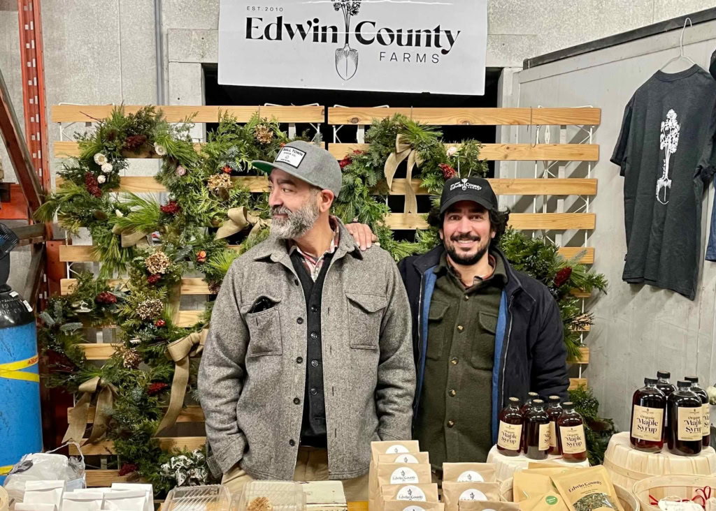 Vibrant farm stand showcasing Edwin County Farms holiday wreaths and local maple syrup.