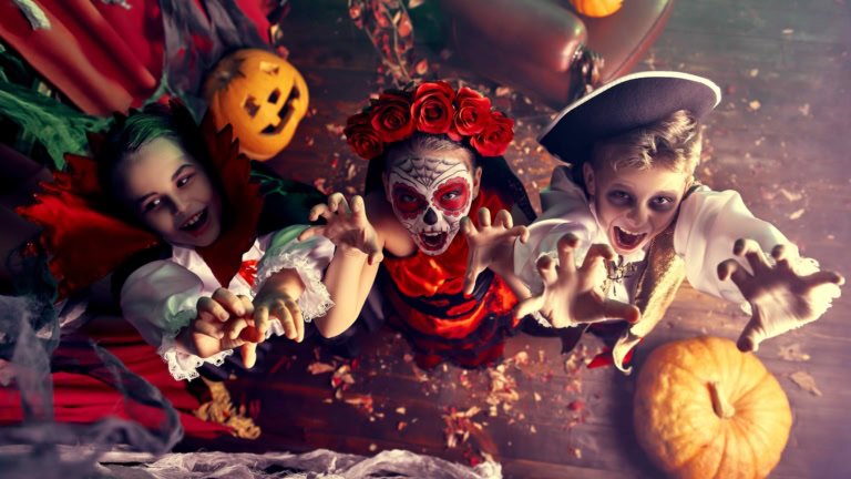Children in Halloween costumes celebrate with pumpkins, cobwebs, and festive decorations.