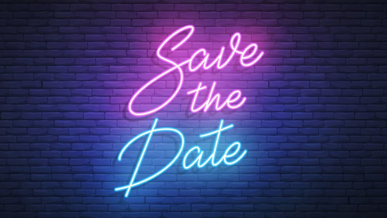 Neon Save the Date sign with pink and blue cursive on a dark brick wall background.