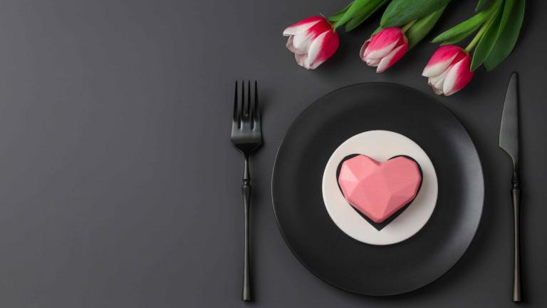 Heart-shaped cake with tulips on elegant table setting, perfect for romantic celebrations.