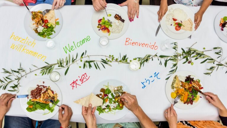 Elegant dinner party with diverse dishes and colorful salads on a white tablecloth.