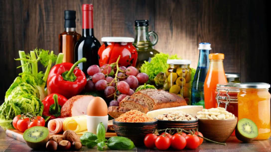 A colorful assortment of fresh ingredients, preserves, and wine, embodying health and culinary abundance.