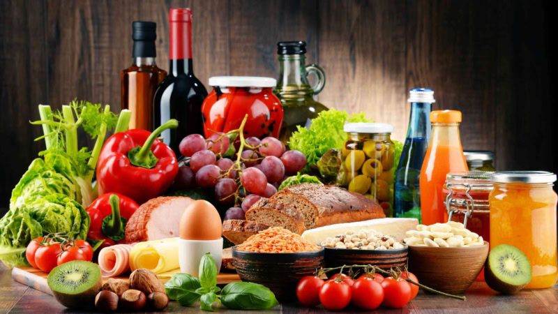 A colorful assortment of fresh ingredients, preserves, and wine, embodying health and culinary abundance.