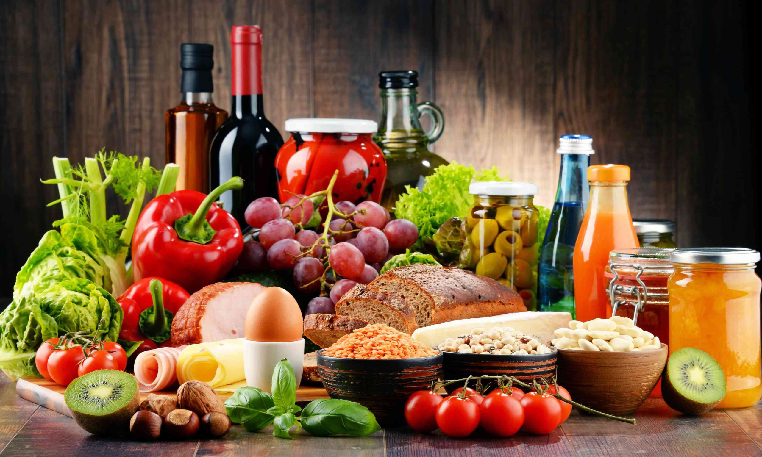 A colorful assortment of fresh ingredients, preserves, and wine, embodying health and culinary abundance.