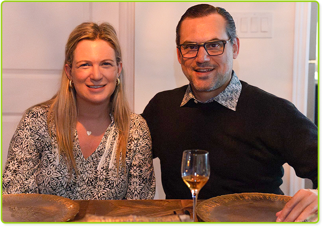Dining table duo sharing smiles and wine in a cozy, warm setting.