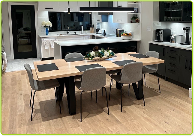 Modern kitchen with wooden dining table, gray chairs, white cabinets, and black countertops.