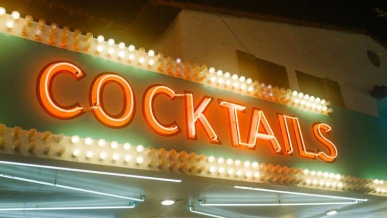 Bright neon cocktail sign at a lively event venue.