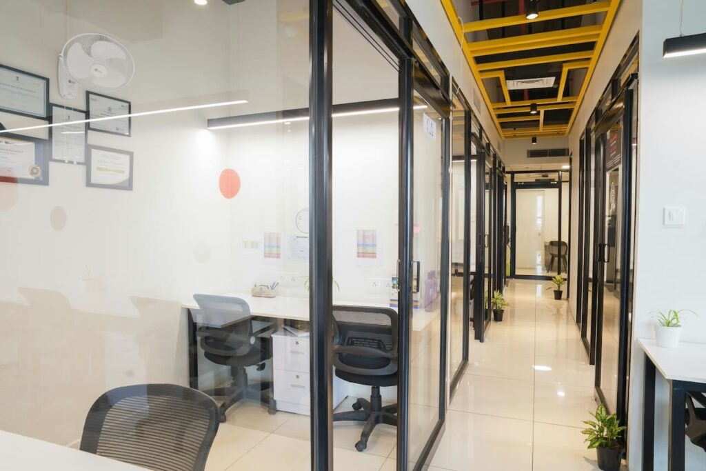 Modern office with glass partitions, natural light, and collaborative workspaces.