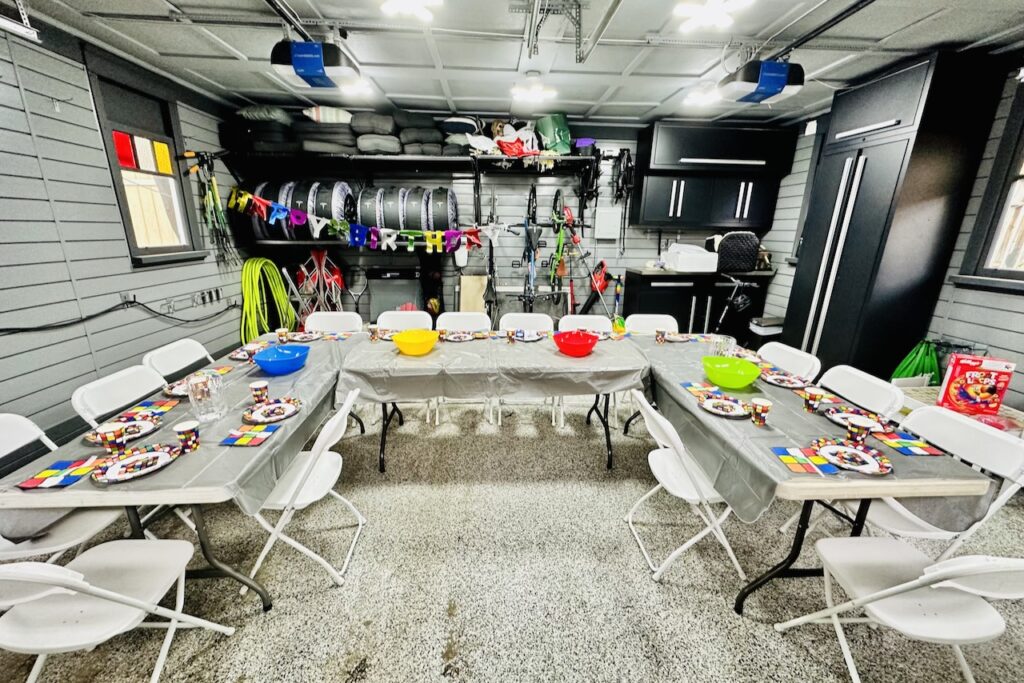 Garage party setup with colorful tables, chairs, and decorations for festive celebration.