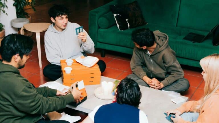 Group of young adults engaging in a small group icebreaker activity indoors.