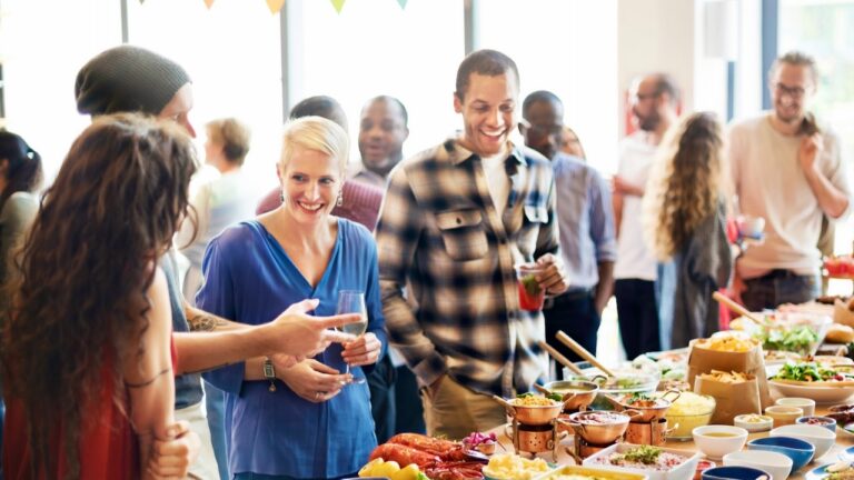 Group of friends enjoying a potluck dinner party with diverse dishes and drinks.