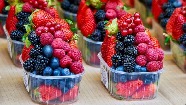 Fresh mixed berries in clear plastic containers, including strawberries, raspberries, blackberries,.