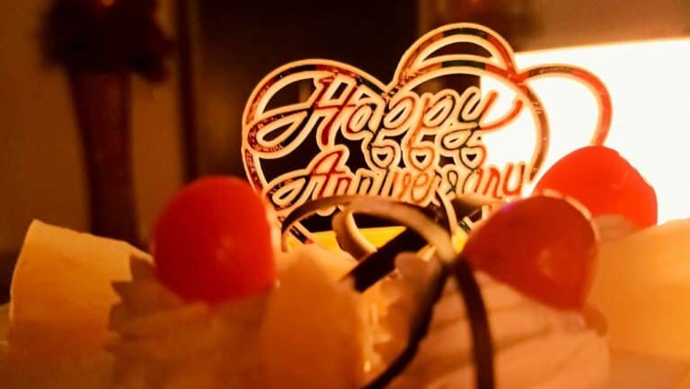 Elegant anniversary cake topped with fresh strawberries and a "Happy Anniversary" topper, perfect fo.