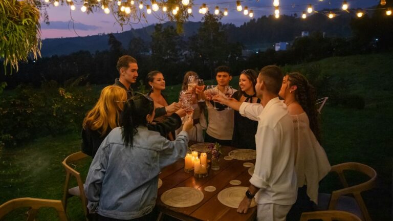 Outdoor backyard dinner party with friends under string lights, celebrating together.