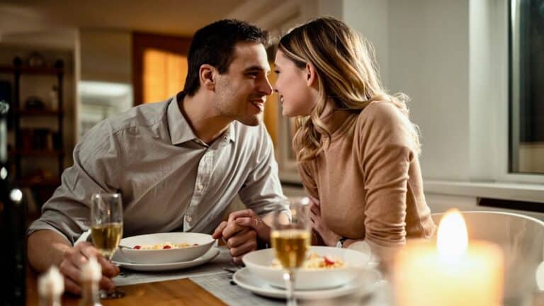 A couple sharing an intimate dinner, smiling and enjoying a cozy night together.