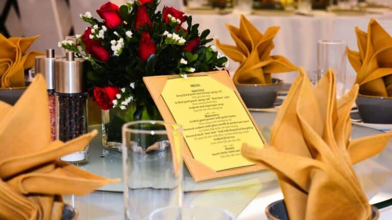 Elegant dinner table setting with floral centerpiece, folded napkins, and menu card for special occa.