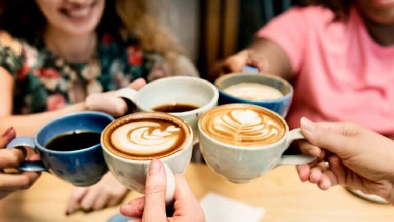 Friends clinking coffee cups during brunch gathering.