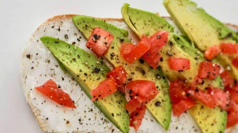 Avocado toast topped with diced tomatoes, black pepper, and fresh herbs, perfect for brunch.