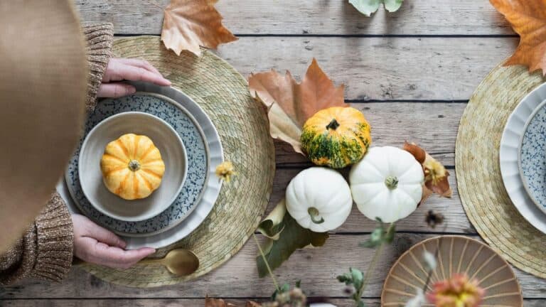 Autumn-themed dinner table with pumpkins, leaves, and elegant place settings for fall celebrations.