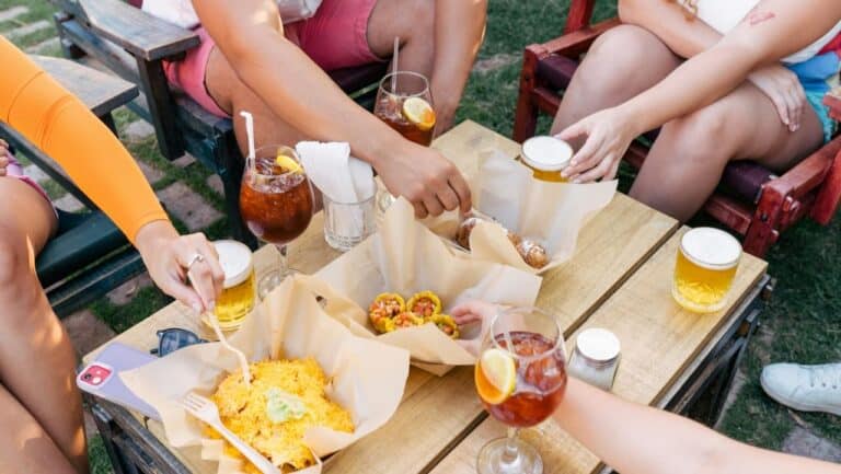 Outdoor backyard entertaining scene with friends enjoying drinks and snacks.