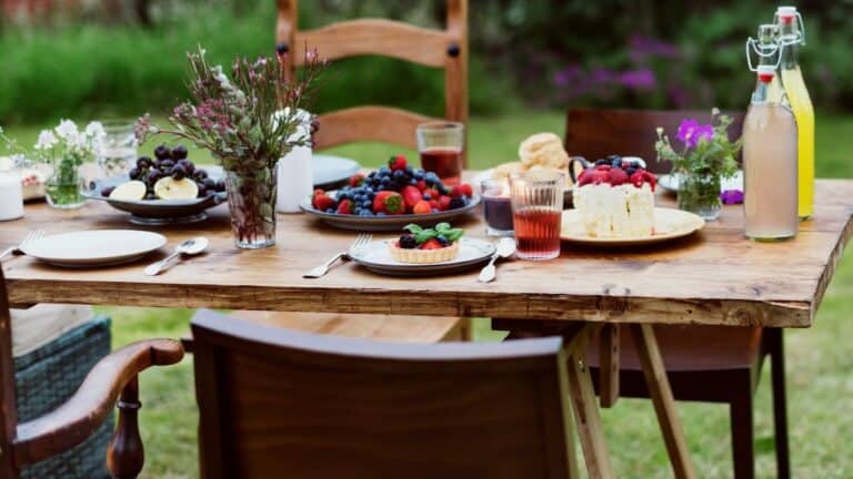 Outdoor backyard dining table with fresh berries, flowers, and beverages for seasonal entertaining.