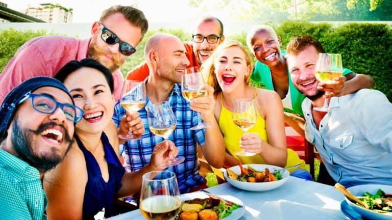 Group of friends enjoying a brunch outdoors with drinks and food.