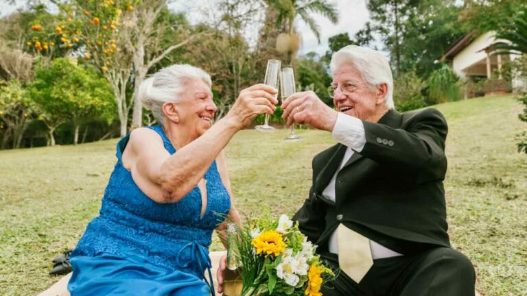 Happy elderly couple toasting with champagne outdoors.