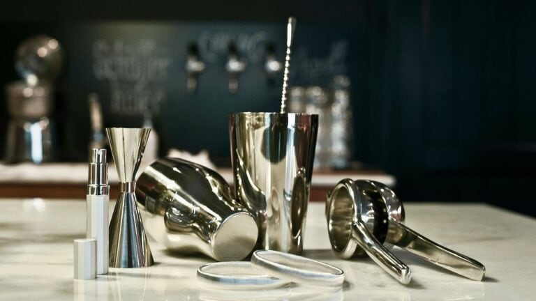 Stylish stainless steel bar tools including shaker, jigger, and strainer for home bar.