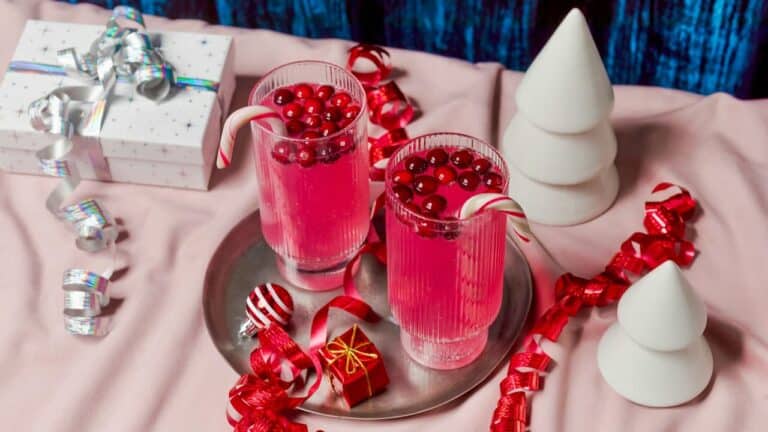 Two vibrant red non-alcoholic cranberry drinks with candy canes on a festive table.