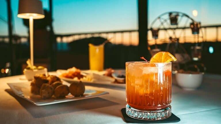 Non-alcoholic cocktail with orange slice on a rooftop table at sunset.