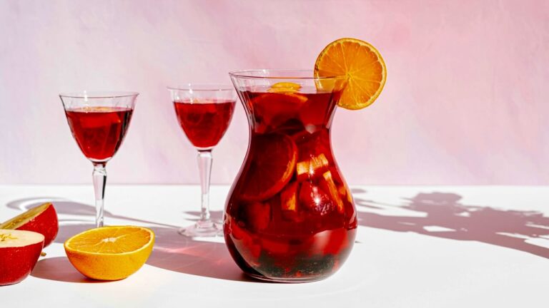 Non-alcoholic fruit punch with orange and lemon slices in a glass pitcher.