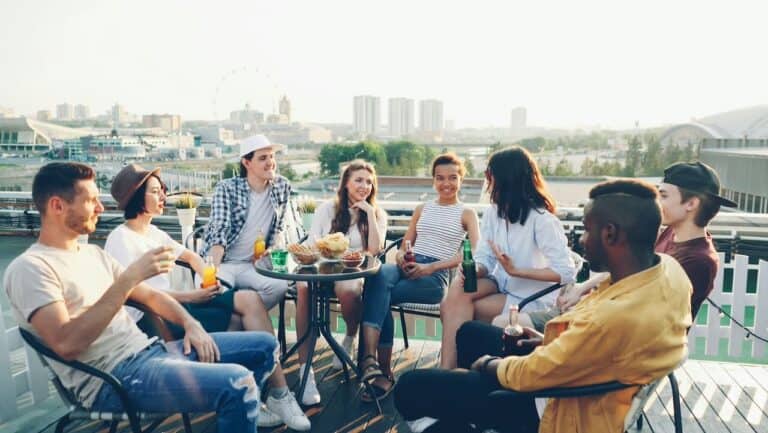 Enjoy a friendly rooftop party with friends, drinks, and engaging conversations in a vibrant outdoor.