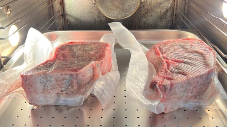 Two seasoned steaks vacuum-sealed in bags, ready for sous vide cooking.