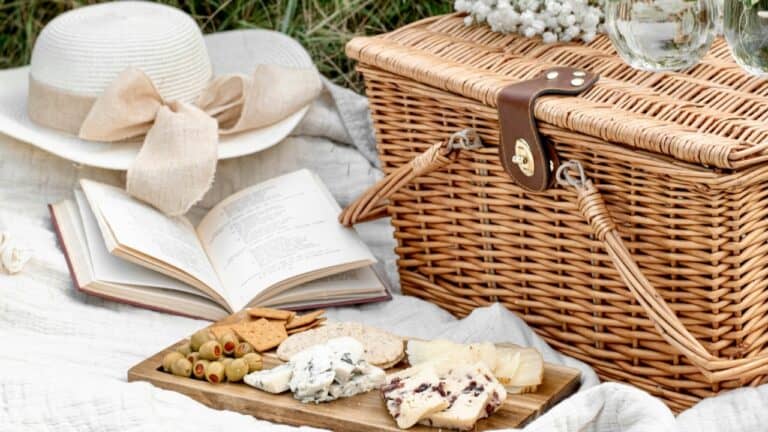 Elegant picnic setup with cheese, crackers, and a wicker basket for outdoor dining.