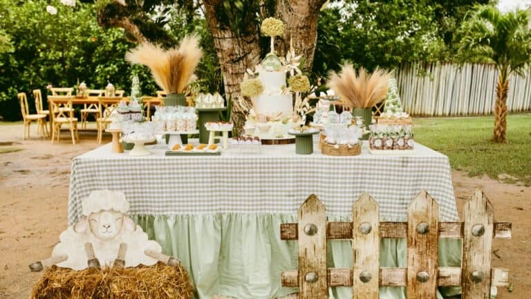 Elegant baby shower dessert table featuring a tiered cake, cupcakes, and rustic decorations in an ou.