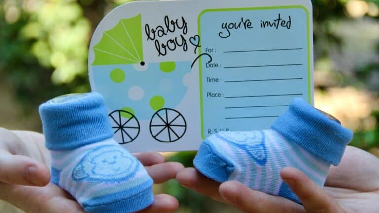 Baby shower invitation card with blue baby socks, green umbrella, and RSVP details for a joyful cele.