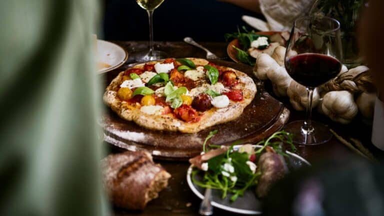 Pizza with fresh vegetables, cheese, and herbs, perfect for outdoor summer dinner parties.