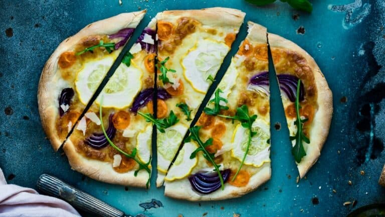 Fresh homemade pizza with cheese, onions, and herbs on a rustic blue background.