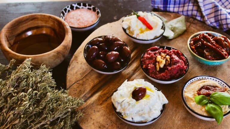 A detailed wooden platter featuring assorted gourmet dips, spreads, and olives for elegant hosting.
