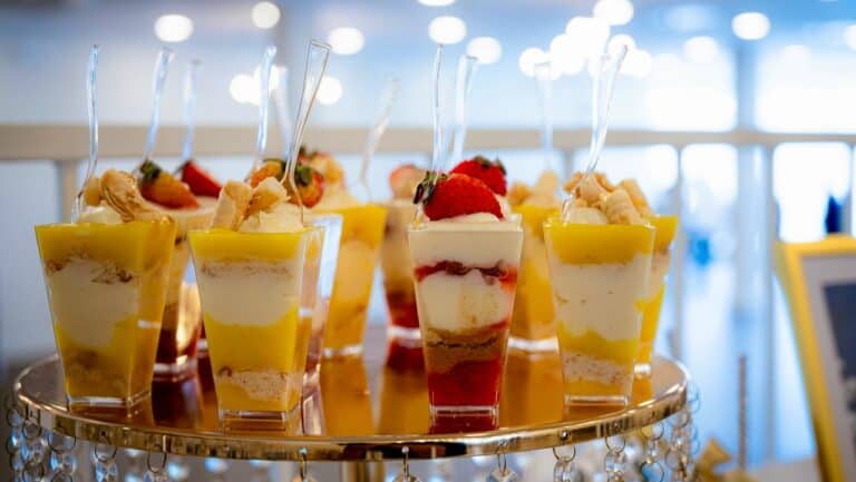 Mini dessert parfaits with fresh fruit and creamy layers on a golden tray at The Gourmet Host.