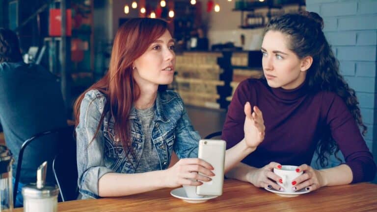 Two women having a serious conversation at a cafe table.