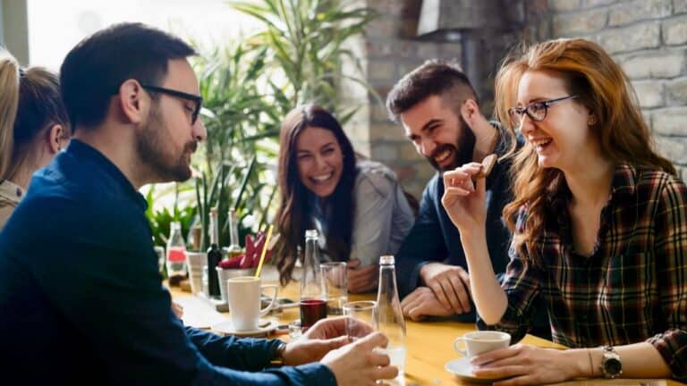 Group of friends enjoying conversation and drinks at a Thanksgiving gathering.