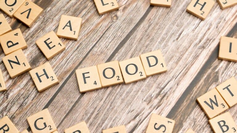 Delicious food arranged with Scrabble tiles on rustic wooden surface for gourmet dining theme.