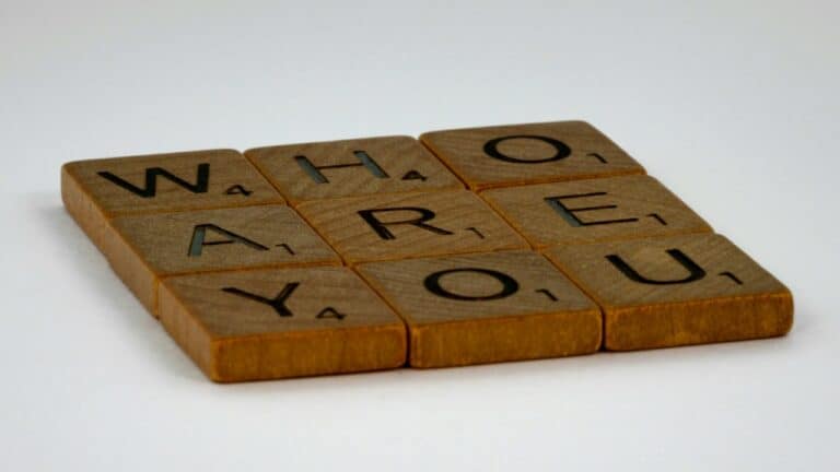 Deluxe Scrabble tiles spelling "Who Are You" on a white background.