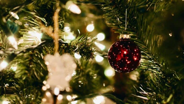 Festive Christmas tree with red ornament and warm glowing lights, holiday celebration decor.