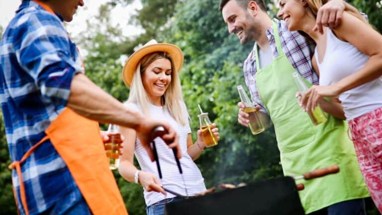 Group of friends enjoying a backyard barbecue with drinks and smiles.
