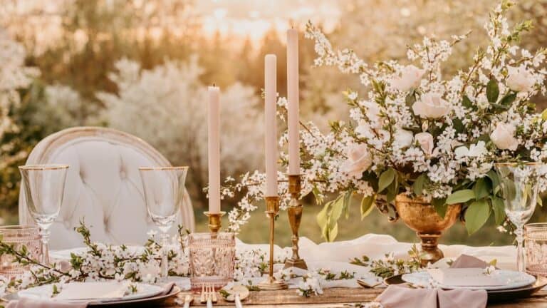 Elegant outdoor bridal shower table with floral arrangements and candles.